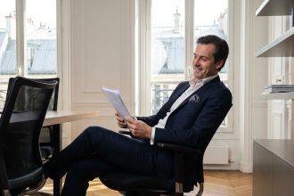 Dirigeant parisien détendu dans son bureau moderne après avoir délégué sa comptabilité à une équipe experte